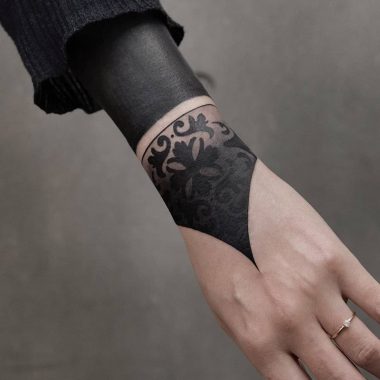 Плотная черная татуировка на руке у девушки