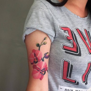 Цветная татуировка орхидей на плече у девушки