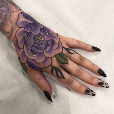 Татуировка фиолетового пиона на кисти у девушки